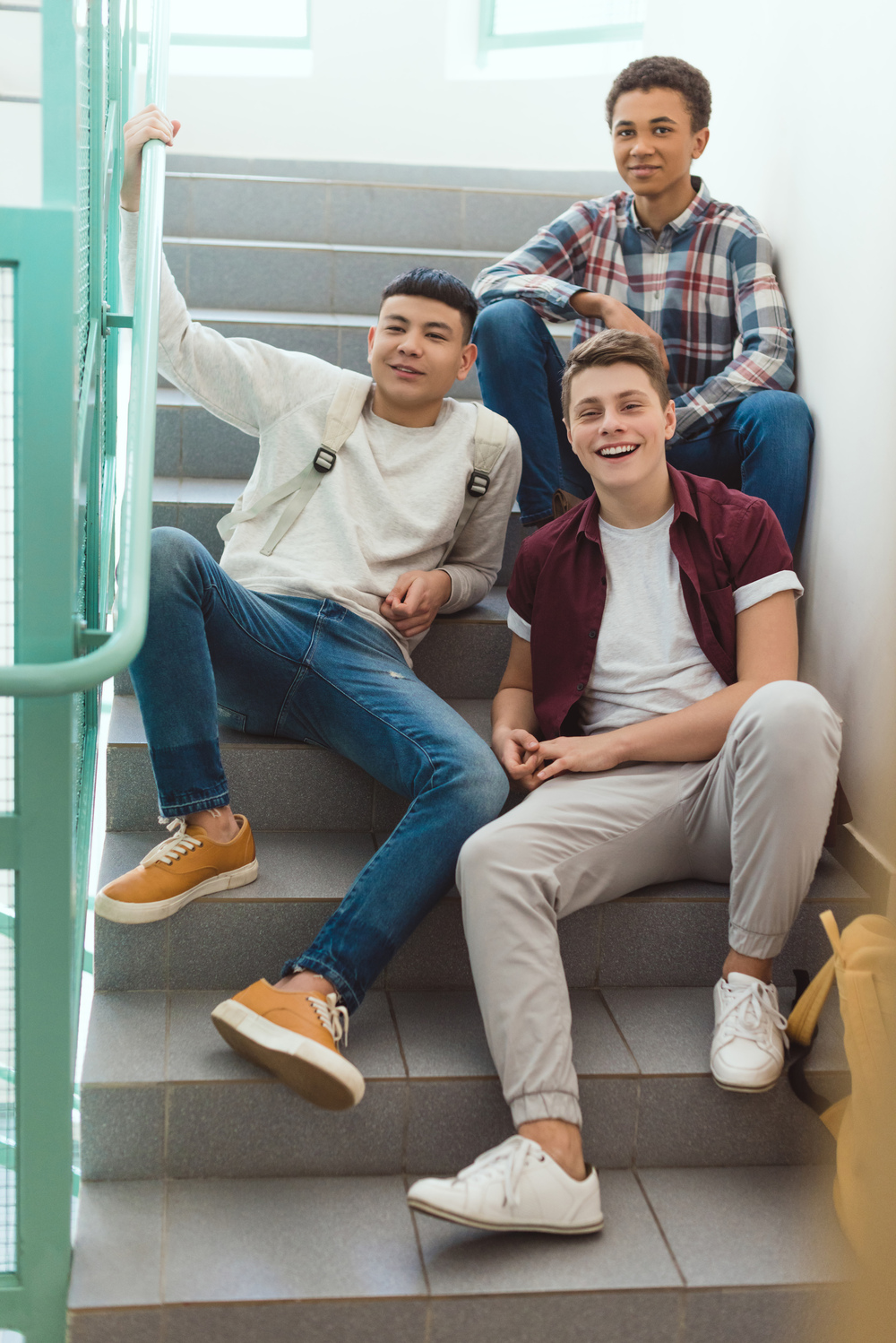 teenage schoolboys sitting on stairs at school and looking at camera