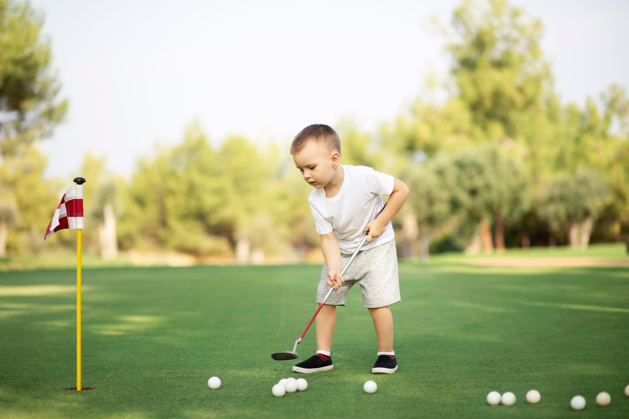 little-boy-playing-golf-with-golf-club-on-green-fi-2023-11-27-05-34-35-utc